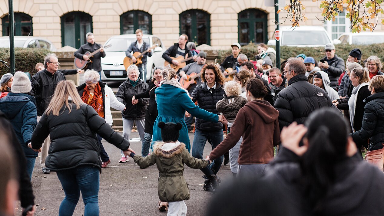 People dance in the street and make music together.